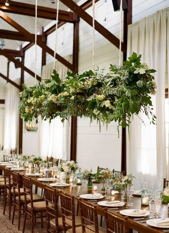 a hanging greenery and white bloom decoration over the reception and matching floral arrangements on the table