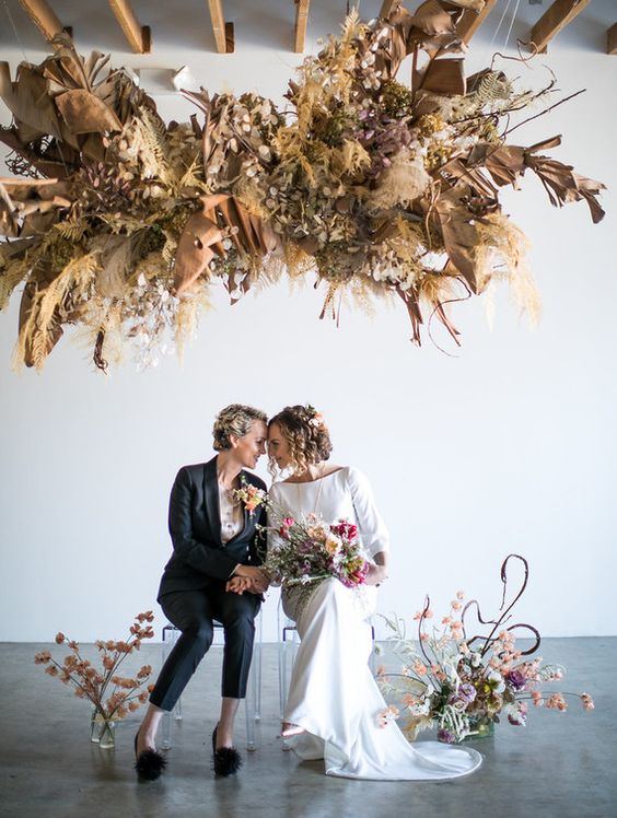 a jaw dropping dried overhead wedding installation with pampas grass and fronds, lunaria and oversized leaves is amazing for a wedding ceremony