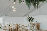 a lovely wedding tablescape with pink and white blooms and greenery, a super lush greenery wedding installation with bulbs hanging down