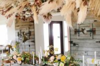 a lush and bold overhead wedding installation with pampas grass, fronds, bold foliage and branches is a lovely addition to fall boho wedding decor