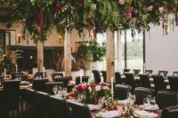 a lush greenery and floral overhead wedding decoration creates a strong wow effect, and an arrangement on the table echoes with it