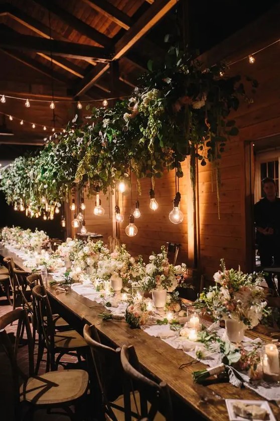 a lush greenery and floral wedding decoration with bulbs for refreshing the indoor space
