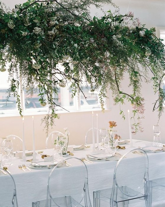 a lush greenery and white bloom wedding installation over the reception table for a refershing spring feel