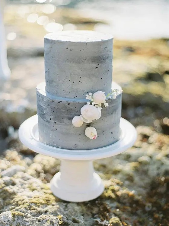 a minimalist grey concrete wedding cake wiht neutral blooms is a very cool idea for a coastal wedding