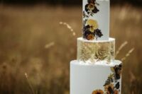 a modern boho wedding cake in white, with rough edges, pressed flowers and leaves, a clear acrylic separator with leaves