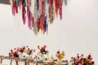 a modern colorful wedding reception space with bright blooms and napkins that echo colorful tinsel fringe over the table