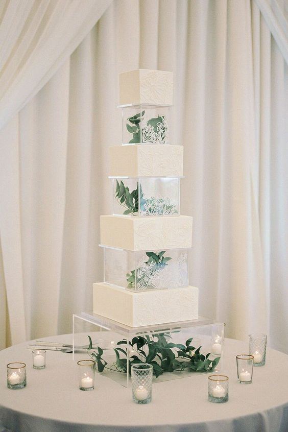 a modern neutral square wedding cake with clear acrylic separators and greenery inside is a cool solution for a modern wedding
