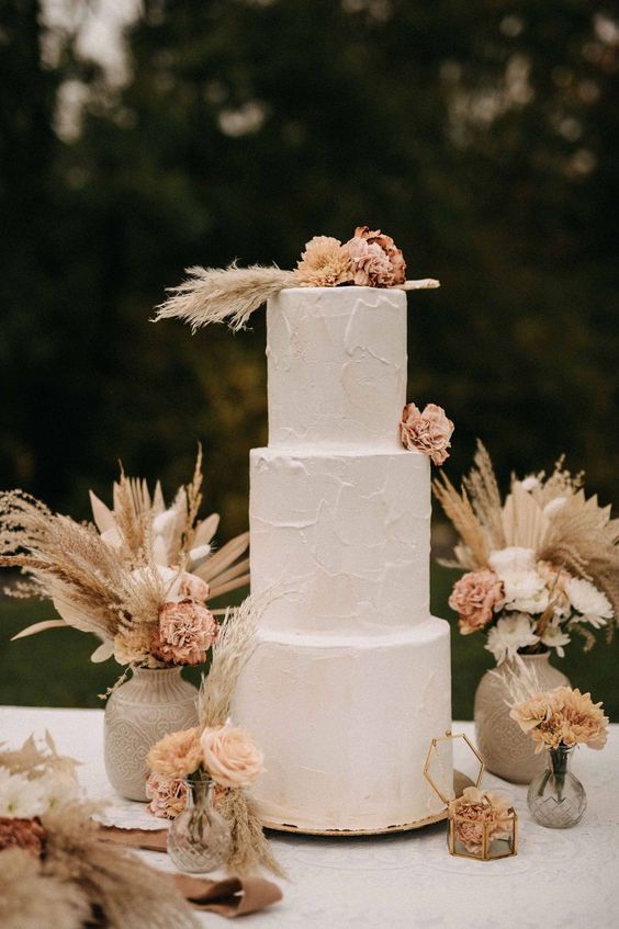 a neutral textural buttercream wedding cake with pastel blooms and pampas grass is a lovely idea for a boho wedding