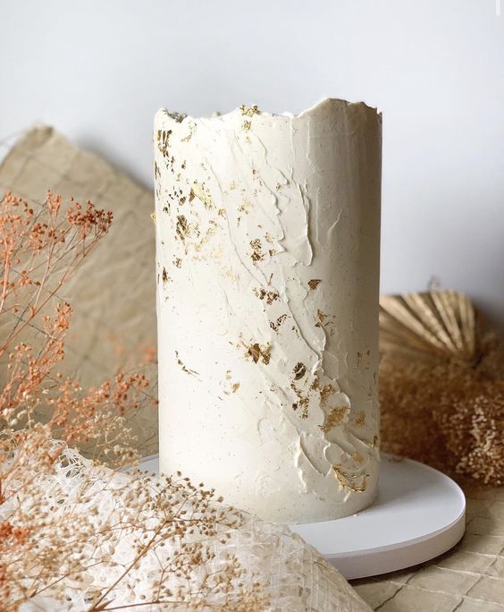 a neutral textural wedding cake with gold glitter and a raw edge is a sophisticated idea for a spring or summer wedding