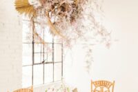 a neutral wedding installation of dried fronds, pink blooms and grasses looks beautiful and delicate and adds chic to the space