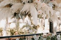 a pampas grass, greenery and blush rose overhead installation will pump your wedding reception and make it look more boho