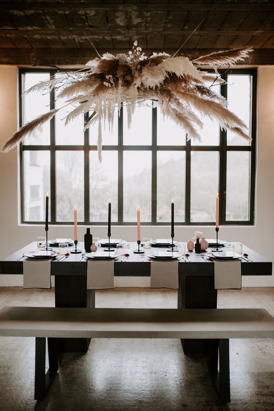 a pampas grass, lunaria, branches overhead wedding installation spruces up the minimalist reception space and adds a wow effect