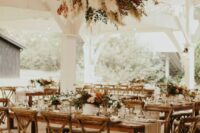 a pretty dried wedding installation of pampas grass, greenery, fall foliage and branches and matching arrangements on the table for a boho rustic wedding