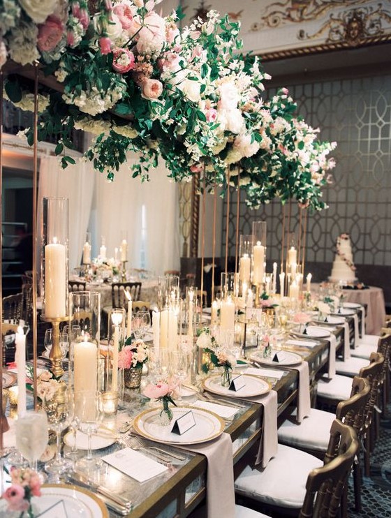 a refined formal wedding reception with a lush decoration of blush blooms and greenery overhead, lots of candles and pink flowers