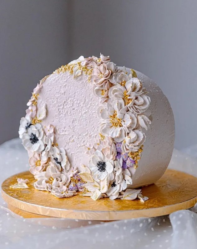 a romantic blush top forward wedding cake decorated with gold pearls and lots of sugar blooms is a lovely idea for a spring or summer wedding