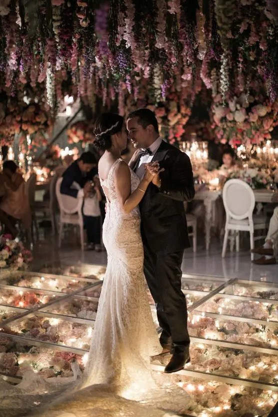a romantic dance floor with lights and fresh blooms under it and bold and pastel blooms over the dance floor is amazing for a glam wedding
