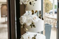 a round white wedding cake accented with clear acrylic separators, white roses and greenery is a very elegant and chic idea