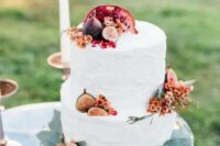a simple and stylish fall wedding cake with bright blooms, pomegranates and figs is an idea that always works