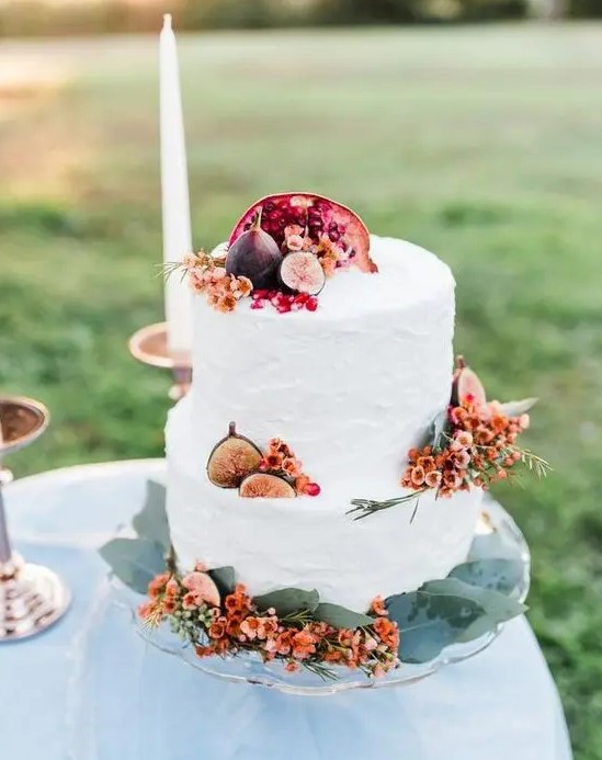 a simple and stylish fall wedding cake with bright blooms, pomegranates and figs is an idea that always works