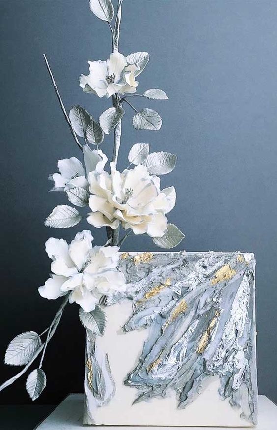 a white square wedding cake with grey buttercream and gold touches, with sugar blooms and silver leaves is a catchy idea