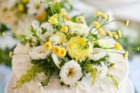 a white textural buttercream wedding cake topped with greenery, white and yellow blooms is a lovely rustic idea for a summer wedding