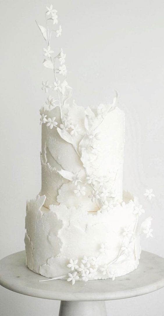 a white textural buttercream wedding cake with a raw edge and some sugar blooms and branches is a fantastic idea for spring and summer