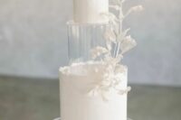 a white textural wedding cake with uneven edges, white sugar branches and a clear acrylic separator right between the tiers