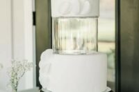 a white wedding cake with an acrylic separator inserted and white textural decor on the tiers is amazing