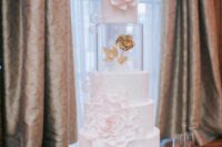 a white wedding cake with bubbles, pearls, large sugar blooms, a clear acrylic separator and a gold rose inside is very exquisite