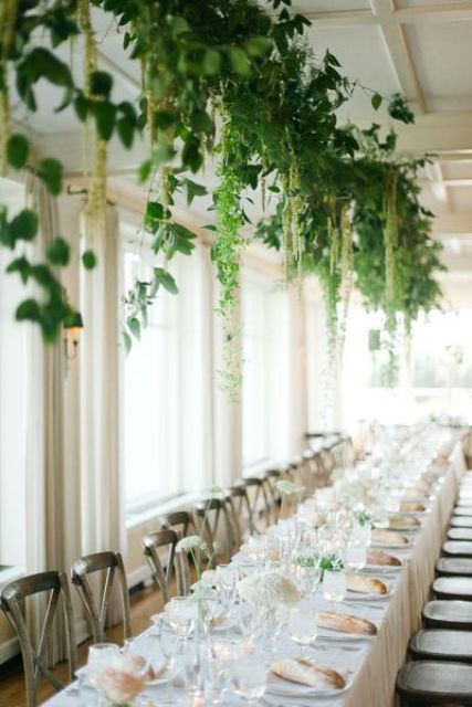 an all-neutral wedding tablescape with white blooms and greenery over the table, with some cascading elements is amazing