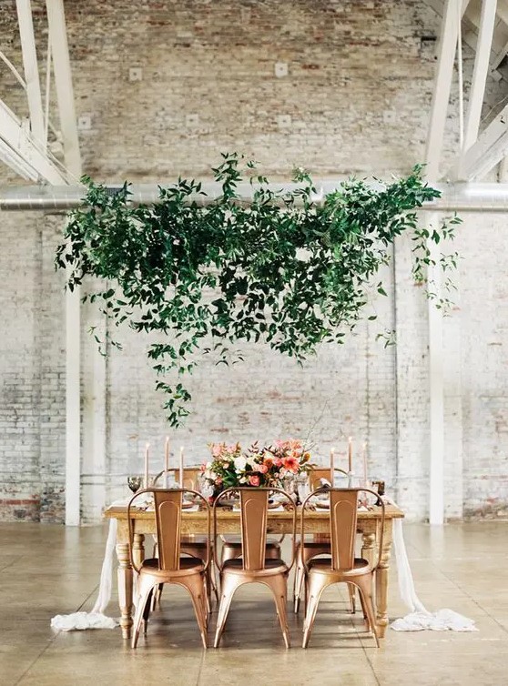 an ethereal overhead greenery decoration adds a soft touch to industrial chairs and a fresh touch