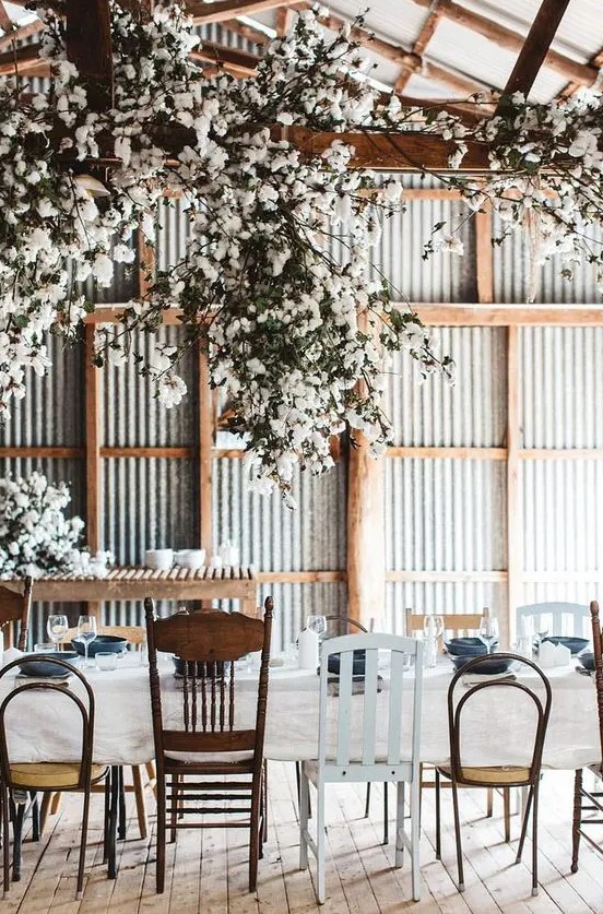 an industrial wedding venue done with corrugated steel, wooden beams, oversized cotton branch chandeliers