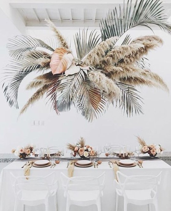 an oversized tropical wedding installation with leaves and pampas grass will make your wedding feel really tropical like
