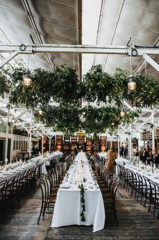 lush greenery overhead decorations with lanterns refresh the indoor venue and make it feel natural