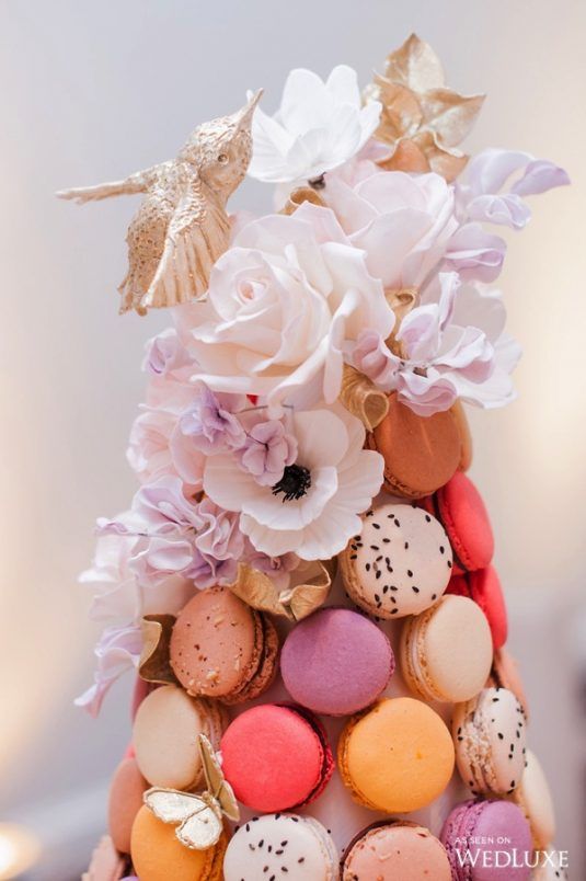 a dreamy colorful macaron tower with gold butterflies, hummingbirds, sugar white and usual white blooms is a very whimsy idea