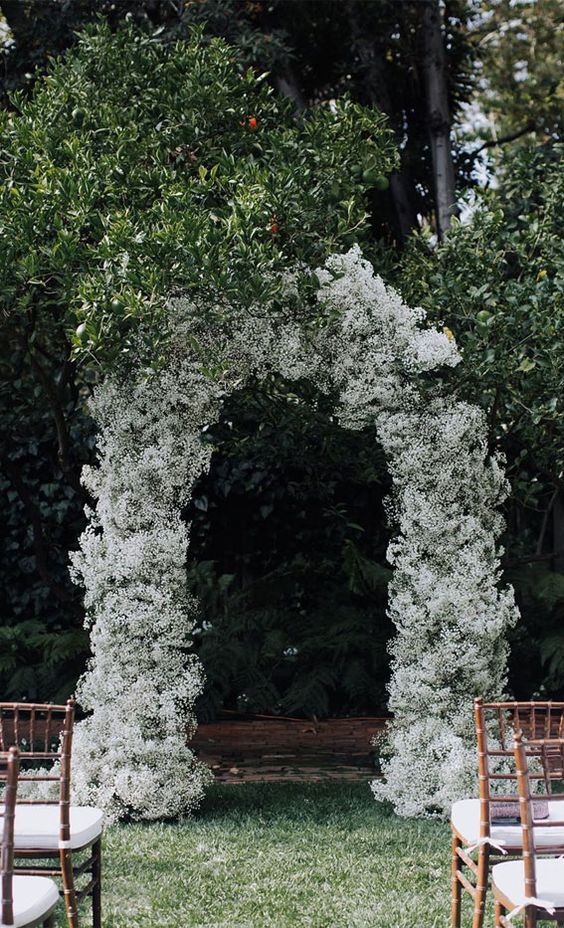 a white baby's breath wedding arch is an elegant and chic wedding decor idea that won't break the bank