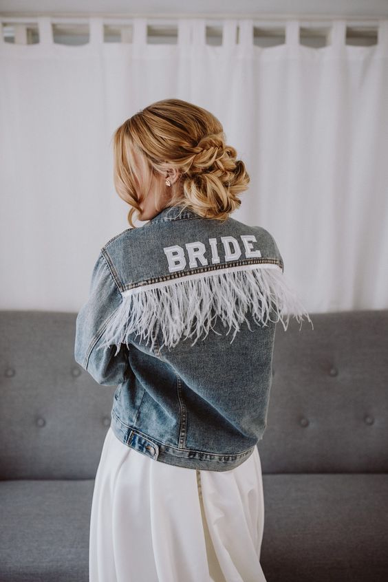 a blue denim bridal jacket personalized with white fringe and letters is a very cool idea for a relaxed boho bridal look
