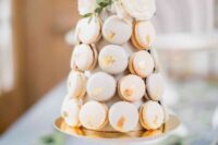 05 a neutral macaron tower cake with gold foil and white blooms and greenery on top is a very chic and refined idea