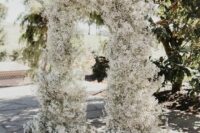 05 a super lush and refined white baby’s breath wedding arch is a timeless and ultimately elegant solution for a wedding