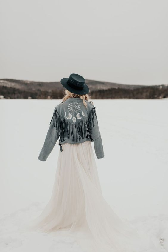 a blue denim bridal jacket with long fringe, calligraphy and celestial painting plus a navy hat for a winter boho bride