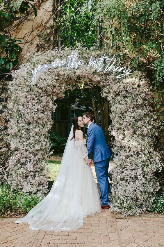 a blush baby's breah wedding arch made bolder with a neon sign is a cool idea for a spring wedding