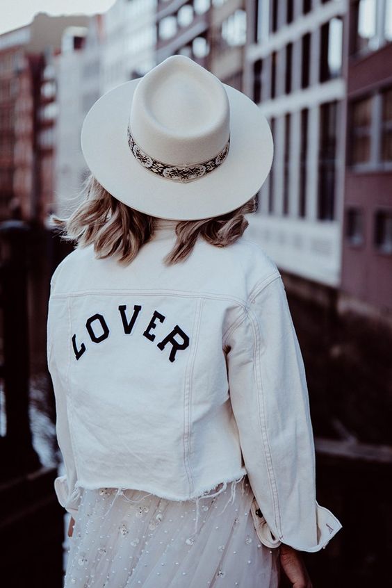 a white denim jacket with black letters and an even edge over an embellished wedding dress for a bold look
