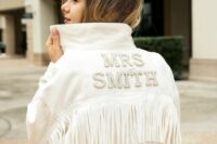 09 a white denim jacket with embellished letters and long fringe is a perfect addition to a boho bridal look