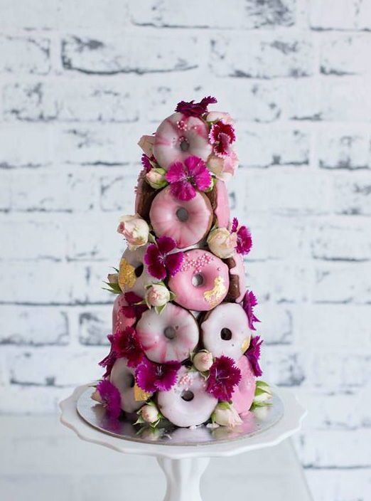 a lovely, cute and whimsy pink glazed donut mini wedding cake decorated with yellow and fuchsia blooms for a bold wedding