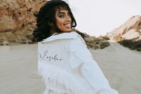 12 a white denim jacket with white fringe and black calligraphy is a catchy and bold idea for a boho bride