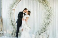 13 a round wedding arch decorated with white baby’s breath and with floating candles in tall glasses for a modern wedding
