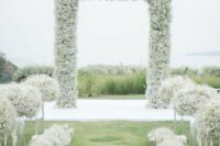14 a stylish modern wedding ceremony space with a baby’s breath arch, tall and low matching arrangements