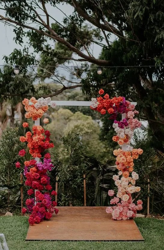a bright wedding arch with a color block effect, with orange, red, hot pink, blush and white roses is wow