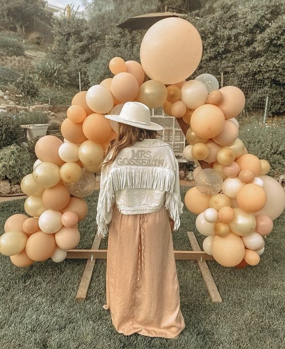 a neutral denim jacket with fringe and gold embroidered letters is a cool idea for a boho bride