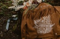20 a brown suede jacket with hand painted white blooms, calligraphy and long fringe on the back is ideal for a boho bride